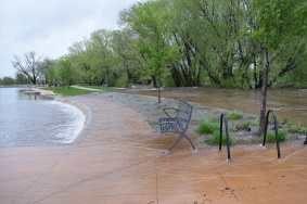The water was spilling over the creek across the sidewalk and bench.